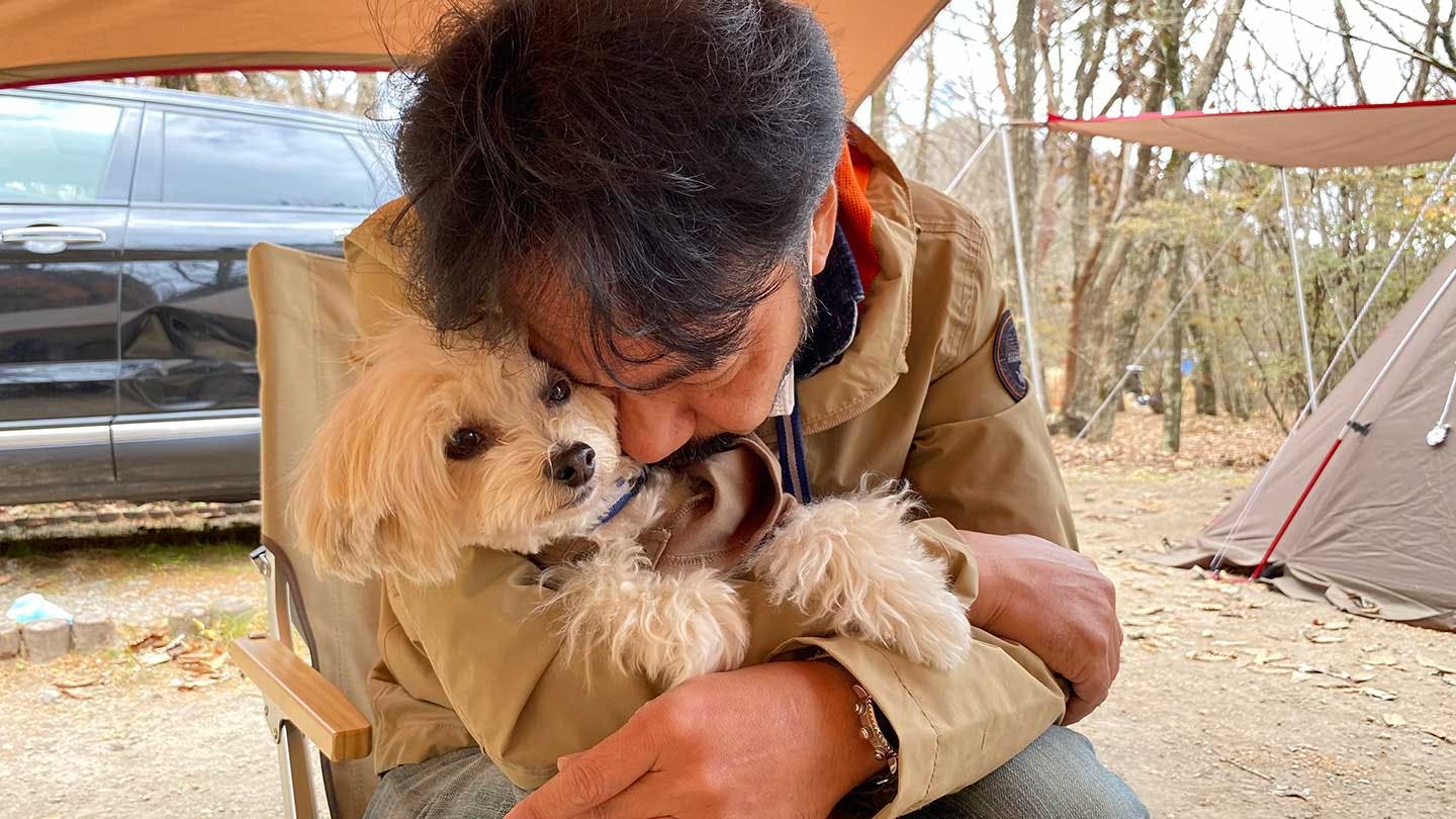 飼い主さんと犬がキャンプ場でのんびりする様子