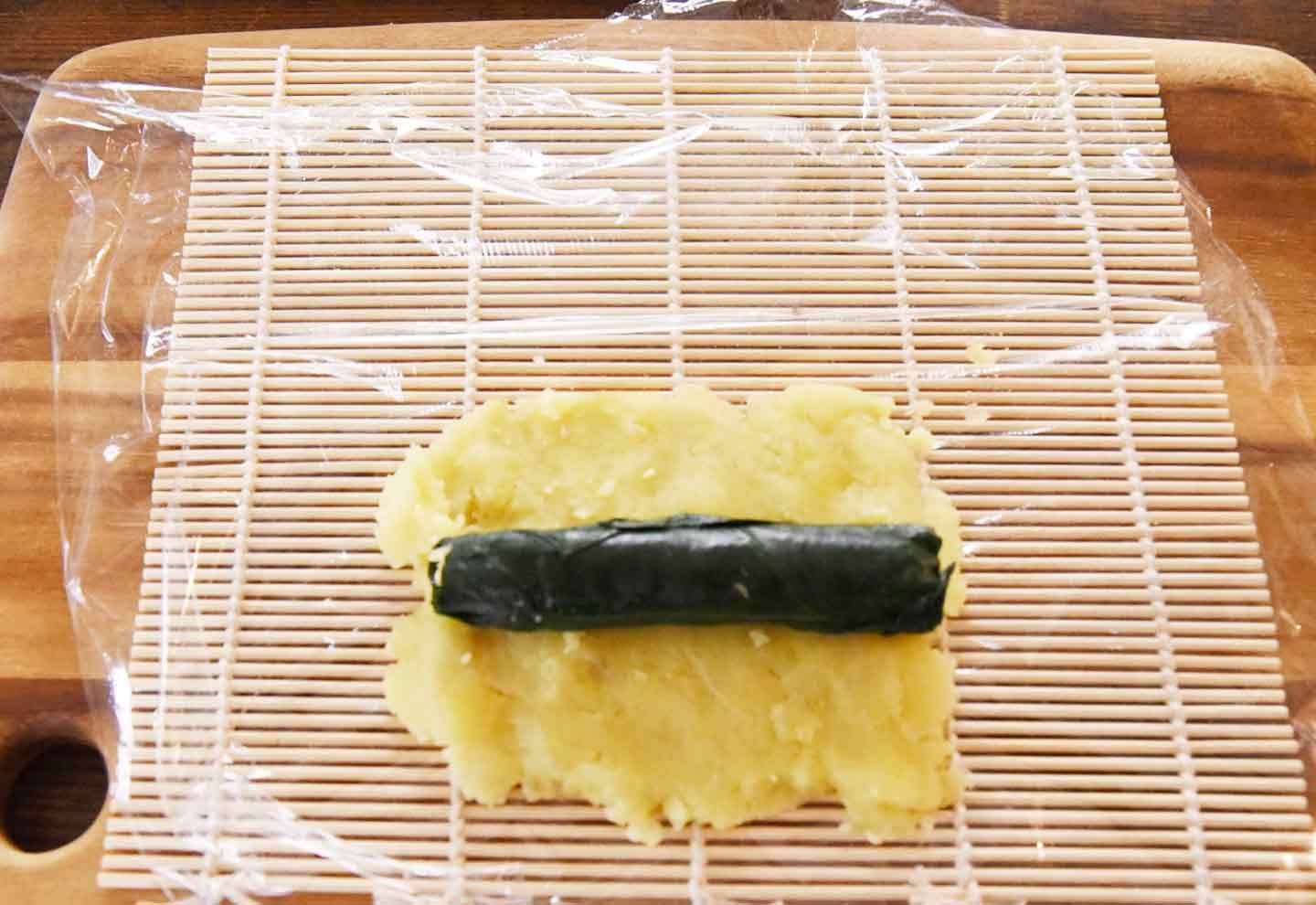 さつまいもにほうれん草で包んだ卵焼きを置く