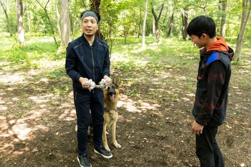 かじりんボーンを手に持つ犬が大好きなライターの竹内と訓練士の稲留さんとジャーマン・シェパードの警察犬パクくん