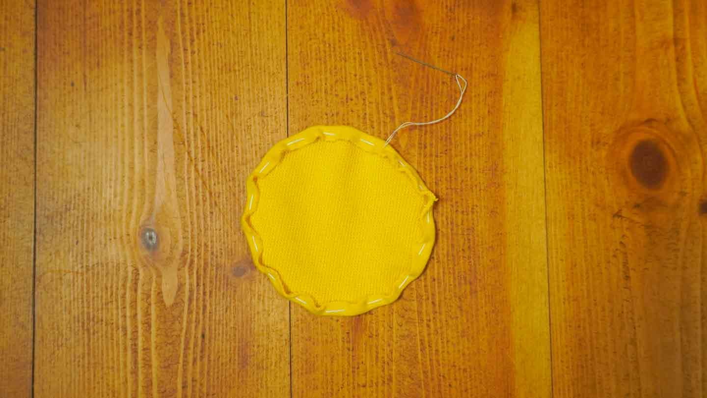 丸くカットした黄色い布を内側に織り込んで縫う